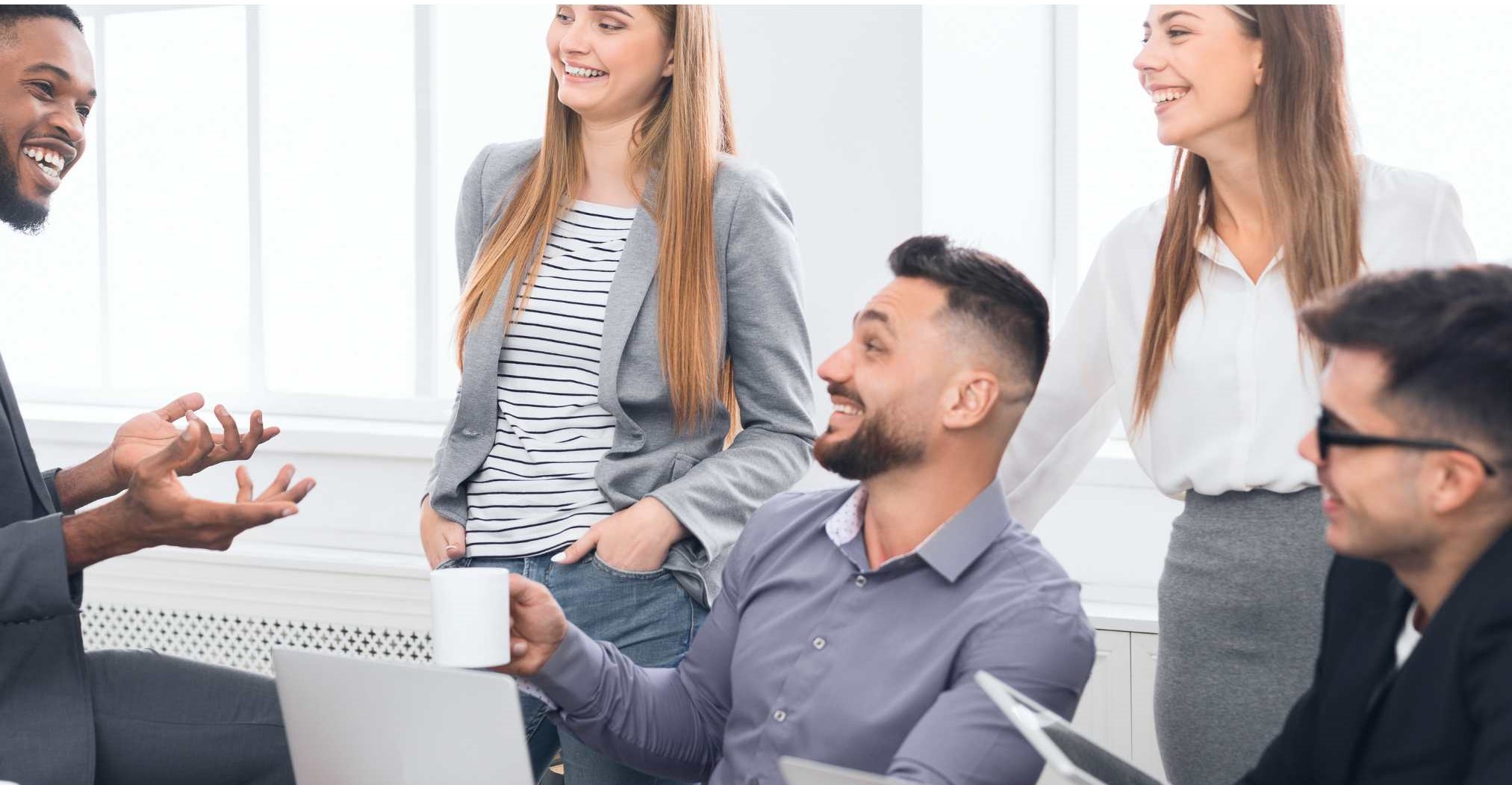 Das Bild zeigt eine Gruppe von Menschen in einem freundlichen Gespräch in einem Büro.