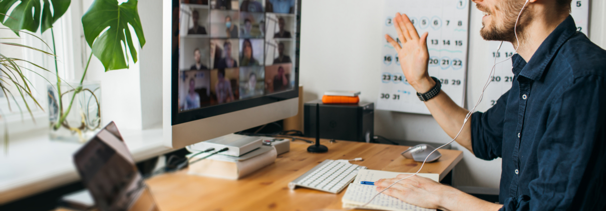 Ein Mann sitzt an einem Schreibtisch und nimmt an einer Videokonferenz auf einem Computerbildschirm teil.