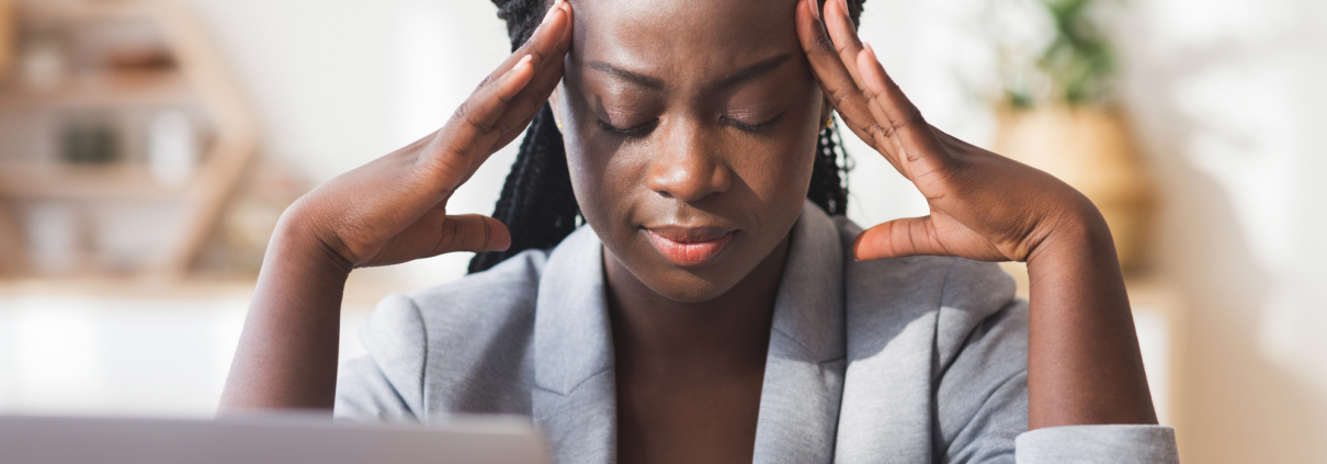 Afro businesswoman massaging temple, trying to concentrate on work