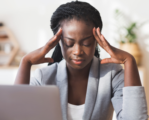 Afro businesswoman massaging temple, trying to concentrate on work