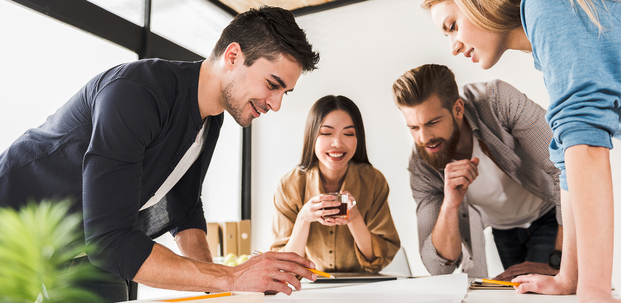 Vier Personen arbeiten gemeinsam an einem Tisch, vertieft in eine Besprechung oder ein Projekt.